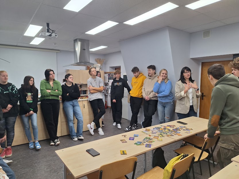 11. un 12. klases skolēni stāv pusaplī un klausās par studiju iespējām Vidzemes augstskolā