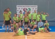 Skolēni zaļos t-kreklos pozē sporta zālē