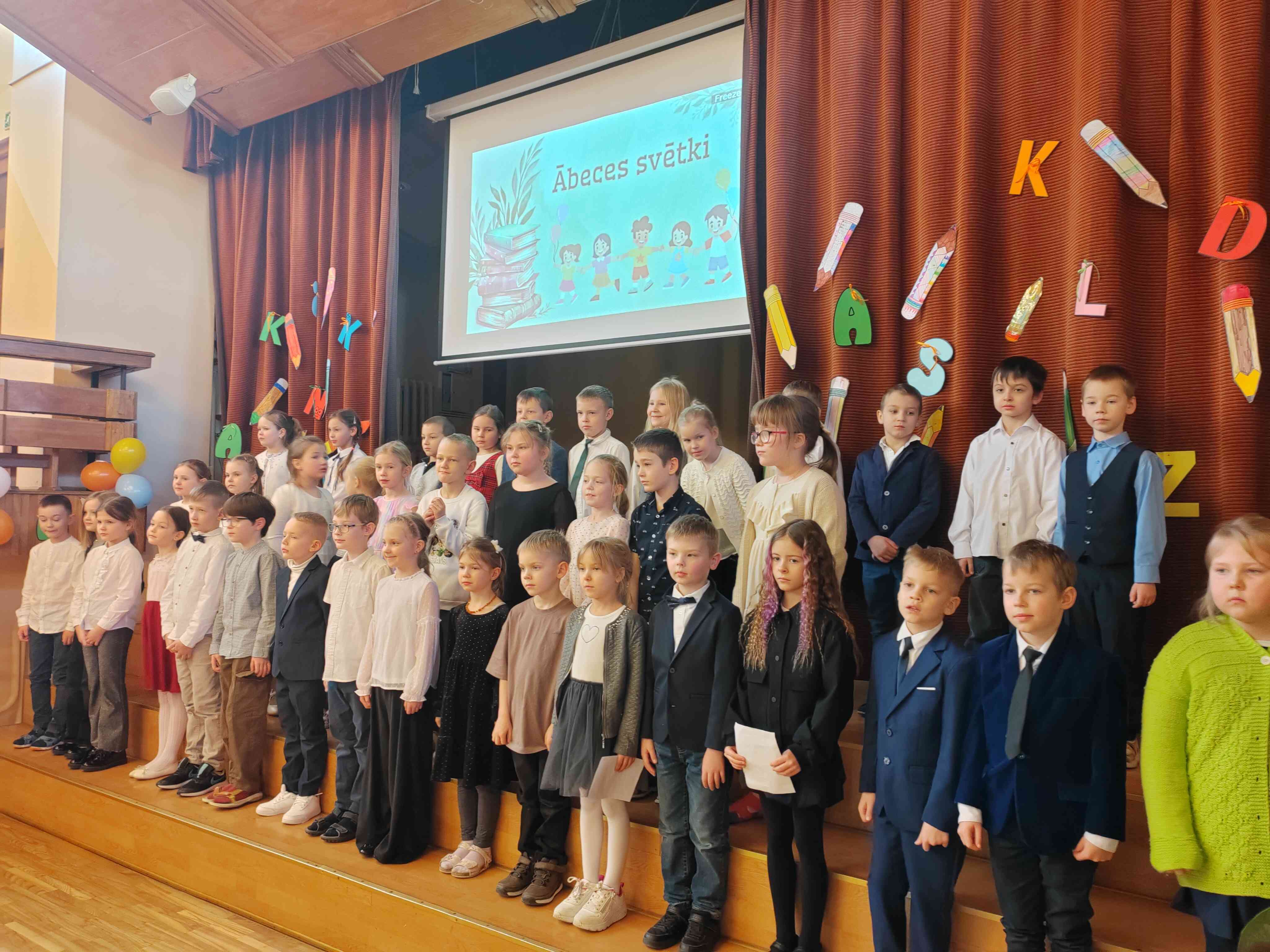 Skolēni stāv uz skatuves