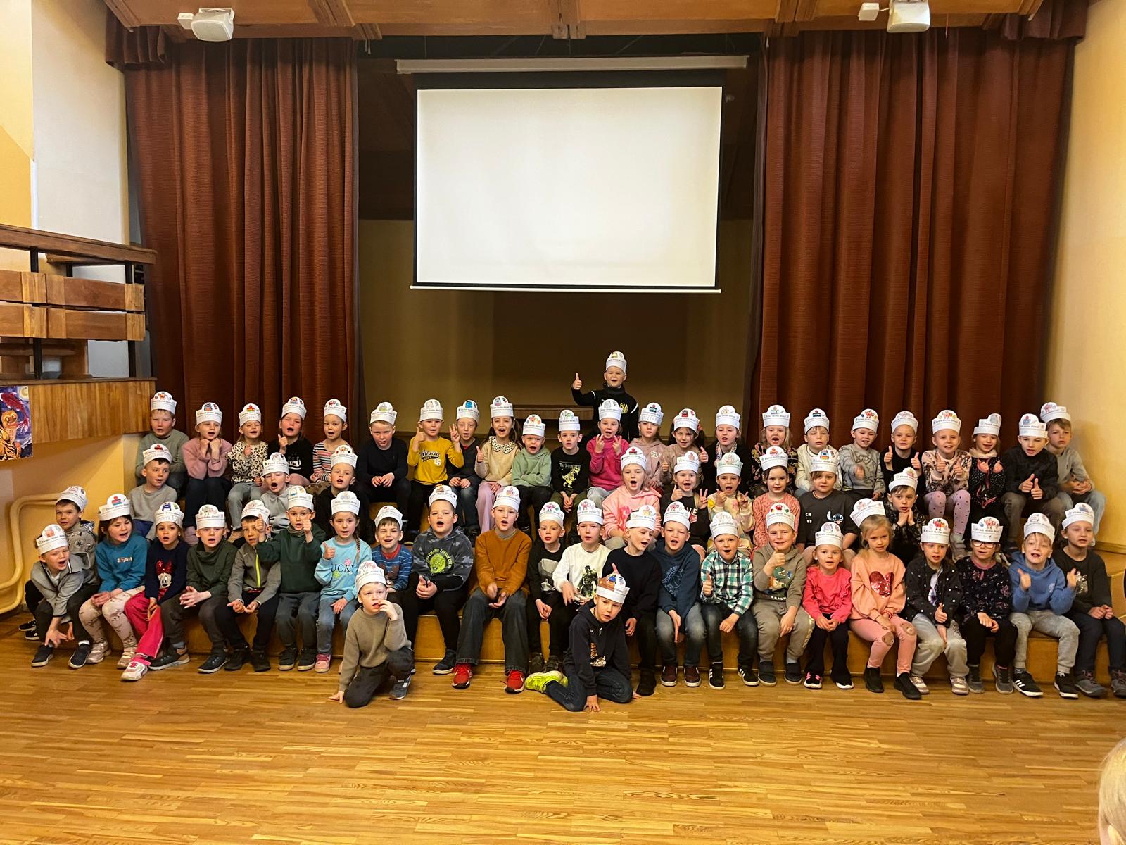 Bērni sēž uz trepēm un rāda īkšķi